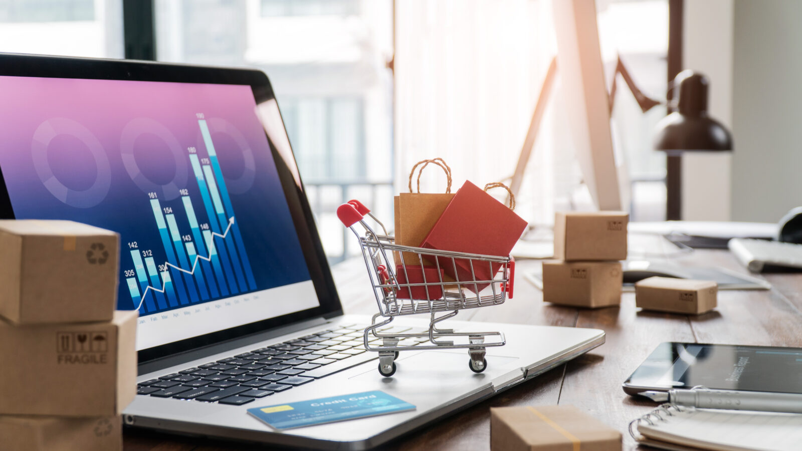 Das Bild zeigt einen Laptop mit einem Miniatur-Einkaufswagen darauf. / Symbolbild für Nischenmarketing im E-Commerce